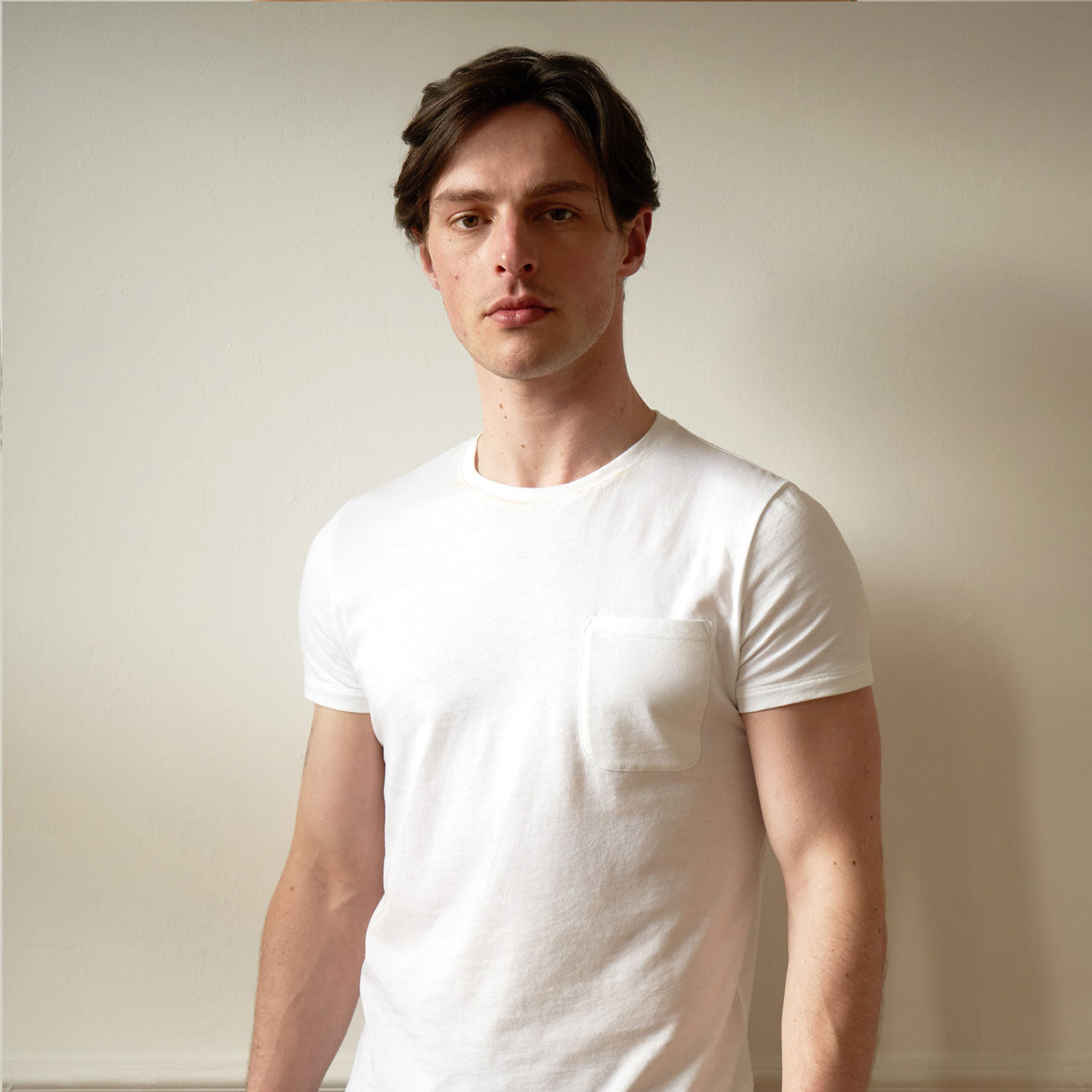 Single Pocket White T shirt. Slim fitting. On Male model size small with dark hair. front view